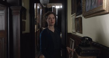 Movie still from “The Last Vermeer” (2019), directed by Dan Friedkin – A woman standing in a room in front of pictures; Medium shot, Low angle