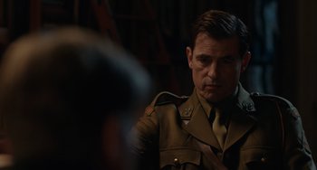 Movie still from “The Last Vermeer” (2019), directed by Dan Friedkin – A man in a military uniform looking at the camera; Close Up shot, Over the shoulder angle