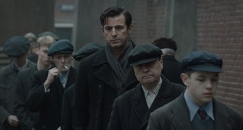 Movie still from “The Last Vermeer” (2019), directed by Dan Friedkin – A group of men walking down a street; Medium shot, Over the shoulder angle