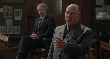 Movie still from “The Last Vermeer” (2019), directed by Dan Friedkin – A man in a suit and tie talking to another man in a suit and tie; Medium shot, Over the shoulder angle