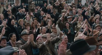 Movie still from “The Last Vermeer” (2019), directed by Dan Friedkin – A group of people sitting in a crowd clapping; Wide shot, High angle