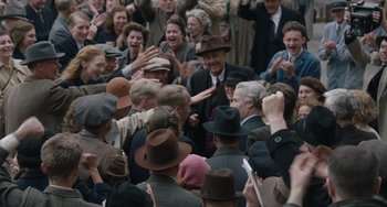 Movie still from “The Last Vermeer” (2019), directed by Dan Friedkin – A group of people in a crowd of people wearing hats; Medium shot, High angle