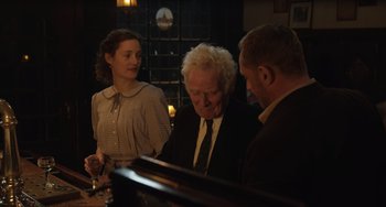 Movie still from “The Last Vermeer” (2019), directed by Dan Friedkin – A man and two women are sitting at a bar; Medium shot, Over the shoulder angle