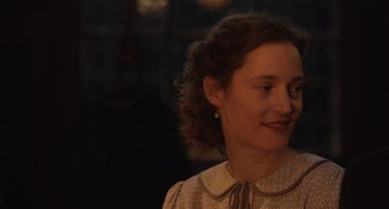 Movie still from “The Last Vermeer” (2019), directed by Dan Friedkin – A woman with curly red hair wearing a dress; Close Up shot, Over the shoulder angle