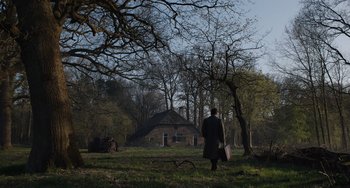 Movie still from “The Last Vermeer” (2019), directed by Dan Friedkin – A man walking in a field near a house; Extreme Wide shot, Low angle