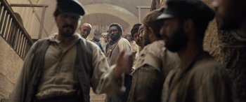 Movie still from “The Last Voyage of the Demeter” (2023), directed by André Øvredal – A group of men standing next to each other in a building; Medium shot, Over the shoulder angle