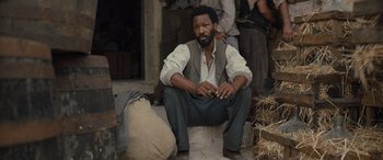 Movie still from “The Last Voyage of the Demeter” (2023), directed by André Øvredal – A man sitting on the ground in front of a group of people; Medium shot, High angle