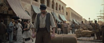 Movie still from “The Last Voyage of the Demeter” (2023), directed by André Øvredal – A man in a hat and vest walking down a street; Medium shot, Over the shoulder angle