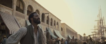 Movie still from “The Last Voyage of the Demeter” (2023), directed by André Øvredal – A man standing in front of a crowd of people; Medium shot, Over the shoulder angle