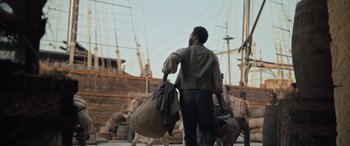 Movie still from “The Last Voyage of the Demeter” (2023), directed by André Øvredal – A man carrying a bag on a boat; Wide shot, Over the shoulder angle