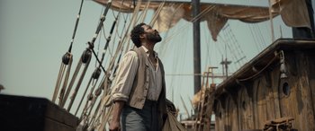 Movie still from “The Last Voyage of the Demeter” (2023), directed by André Øvredal – A man standing on top of a boat in the water; Medium shot, Low angle