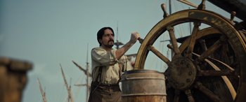 Movie still from “The Last Voyage of the Demeter” (2023), directed by André Øvredal – A man holding a steering wheel on a boat; Medium shot, Low angle