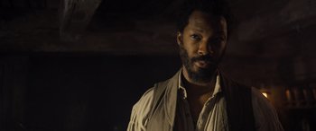 Movie still from “The Last Voyage of the Demeter” (2023), directed by André Øvredal – A man with a black beard and a brown shirt; Close Up shot, Over the shoulder angle