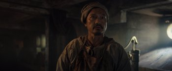 Movie still from “The Last Voyage of the Demeter” (2023), directed by André Øvredal – A man wearing a hat and a apron; Close Up shot, Low angle