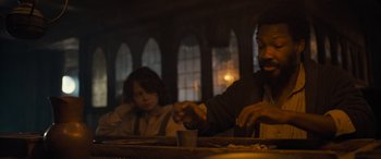 Movie still from “The Last Voyage of the Demeter” (2023), directed by André Øvredal – A man and a woman sitting at a dinner table; Medium shot, Over the shoulder angle