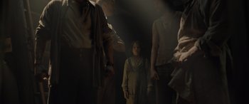 Movie still from “The Last Voyage of the Demeter” (2023), directed by André Øvredal – A group of people standing in a dark room; Medium shot, High angle