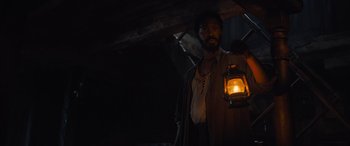 Movie still from “The Last Voyage of the Demeter” (2023), directed by André Øvredal – A man holding a lantern while standing in a dark room; Medium shot, Low angle