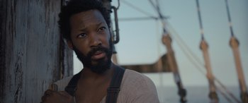 Movie still from “The Last Voyage of the Demeter” (2023), directed by André Øvredal – A person with a beard looking at the camera; Close Up shot, Low angle