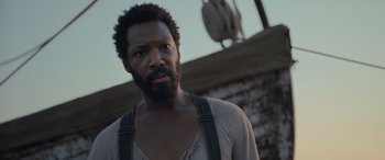 Movie still from “The Last Voyage of the Demeter” (2023), directed by André Øvredal – A man with a beard is standing in front of a building; Close Up shot, Low angle