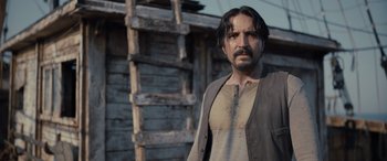 Movie still from “The Last Voyage of the Demeter” (2023), directed by André Øvredal – A man standing in front of a wooden structure; Close Up shot, Over the shoulder angle