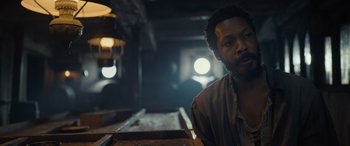 Movie still from “The Last Voyage of the Demeter” (2023), directed by André Øvredal – A man sitting at a table in a dark room; Close Up shot, Low angle