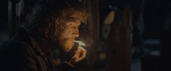 Movie still from “The Last Voyage of the Demeter” (2023), directed by André Øvredal – A man with a beard is lighting a candle in his mouth; Close Up shot, Low angle