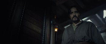 Movie still from “The Last Voyage of the Demeter” (2023), directed by André Øvredal – A man standing next to a lamp post in a dark room; Medium shot, Low angle