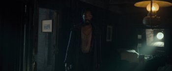 Movie still from “The Last Voyage of the Demeter” (2023), directed by André Øvredal – A man standing in a dark room wearing a coat; Medium shot, Low angle