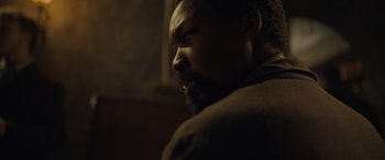 Movie still from “The Last Voyage of the Demeter” (2023), directed by André Øvredal – A person with a beard looking to the side; Close Up shot, High angle