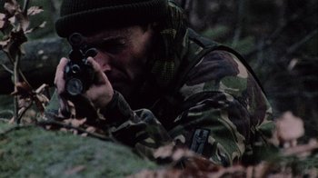 Movie still from “Dog Soldiers” (2002), directed by Neil Marshall – A man in a camouflage jacket is aiming with a rifle; Medium shot, High angle