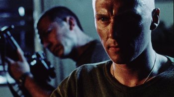Movie still from “Dog Soldiers” (2002), directed by Neil Marshall – A man in a green shirt and another man in a black shirt; Close Up shot, Low angle