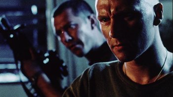 Movie still from “Dog Soldiers” (2002), directed by Neil Marshall – Two men are standing in a room holding guns; Close Up shot, Low angle