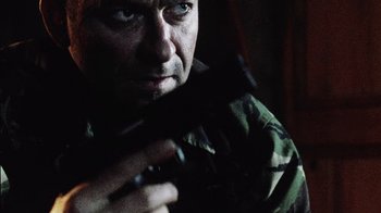 Movie still from “Dog Soldiers” (2002), directed by Neil Marshall – A man holding a gun while wearing a uniform; Close Up shot, Low angle