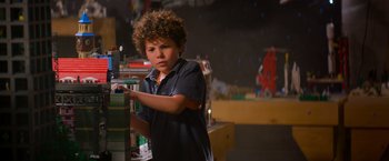 Movie still from “The Lego Movie” (2014), directed by Phil Lord – A young boy standing in front of a stack of books; Medium shot, Over the shoulder angle