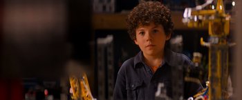 Movie still from “The Lego Movie” (2014), directed by Phil Lord – A young boy with curly brown hair is looking at the camera; Close Up shot, Over the shoulder angle
