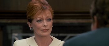 An older woman with red hair wearing a white dress
