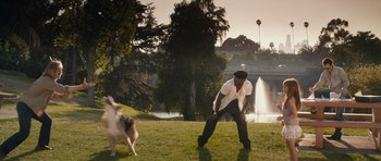 Movie still from “The Lincoln Lawyer” (2011), directed by Brad Furman – A man and a dog in a park with trees in the background; Wide shot, Over the shoulder angle