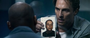 Movie still from “The Lincoln Lawyer” (2011), directed by Brad Furman – A man holding up a picture of a man in jail; Close Up shot, Over the shoulder angle
