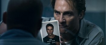 Movie still from “The Lincoln Lawyer” (2011), directed by Brad Furman – A man holding up a picture of a man in jail; Close Up shot, Over the shoulder angle