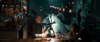 Movie still from “The Lincoln Lawyer” (2011), directed by Brad Furman – A man sitting at a table in front of a bunch of light bulbs; Medium shot, Over the shoulder angle