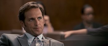 Movie still from “The Lincoln Lawyer” (2011), directed by Brad Furman – A man in a suit and tie sitting in front of some people; Close Up shot, Over the shoulder angle