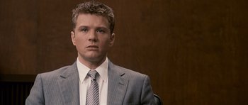Movie still from “The Lincoln Lawyer” (2011), directed by Brad Furman – A man wearing a suit and tie in front of a brown wall; Close Up shot, Over the shoulder angle