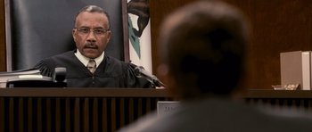 Movie still from “The Lincoln Lawyer” (2011), directed by Brad Furman – A man in a courtroom with a judge's microphone; Close Up shot, Over the shoulder angle