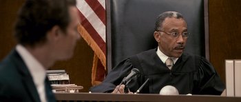 Movie still from “The Lincoln Lawyer” (2011), directed by Brad Furman – A judge in a courtroom with a microphone; Close Up shot, Over the shoulder angle