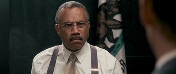 Movie still from “The Lincoln Lawyer” (2011), directed by Brad Furman – An older man wearing a tie and suspenders in front of a flag; Close Up shot, Low angle