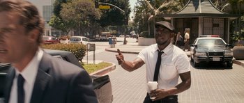 Movie still from “The Lincoln Lawyer” (2011), directed by Brad Furman – A man holding a cup of coffee on the side of the street; Medium shot, Over the shoulder angle