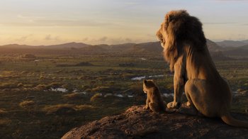 Movie still from “The Lion King” (2019), directed by Jon Favreau – A lion standing on top of a rock next to a cat; Wide shot, Low angle