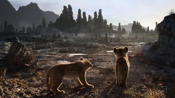 Movie still from “The Lion King” (2019), directed by Jon Favreau – A couple of animals that are standing in the dirt; Wide shot, Low angle