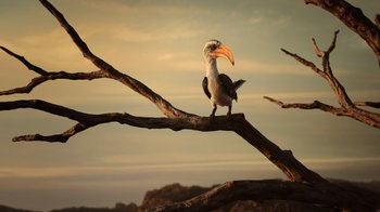 Movie still from “The Lion King” (2019), directed by Jon Favreau – A bird perched on top of a tree branch; Extreme Wide shot, Low angle