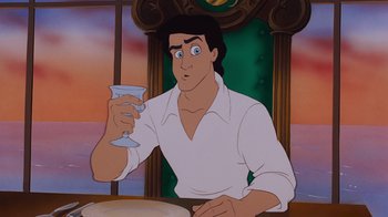 Movie still from “The Little Mermaid” (1989), directed by John Musker – A man holding a wine glass while sitting at a dinner table; Medium shot, High angle